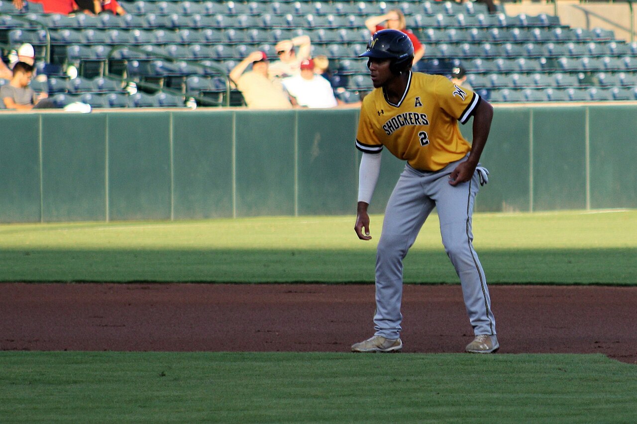 A base runner leading off second base during a college baseball game
