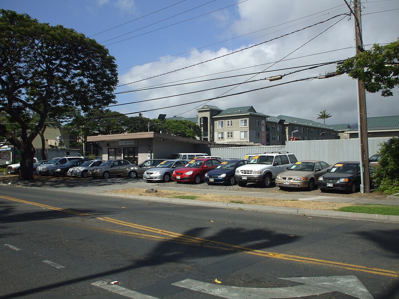 A small used car lot with price stickers in the windshields